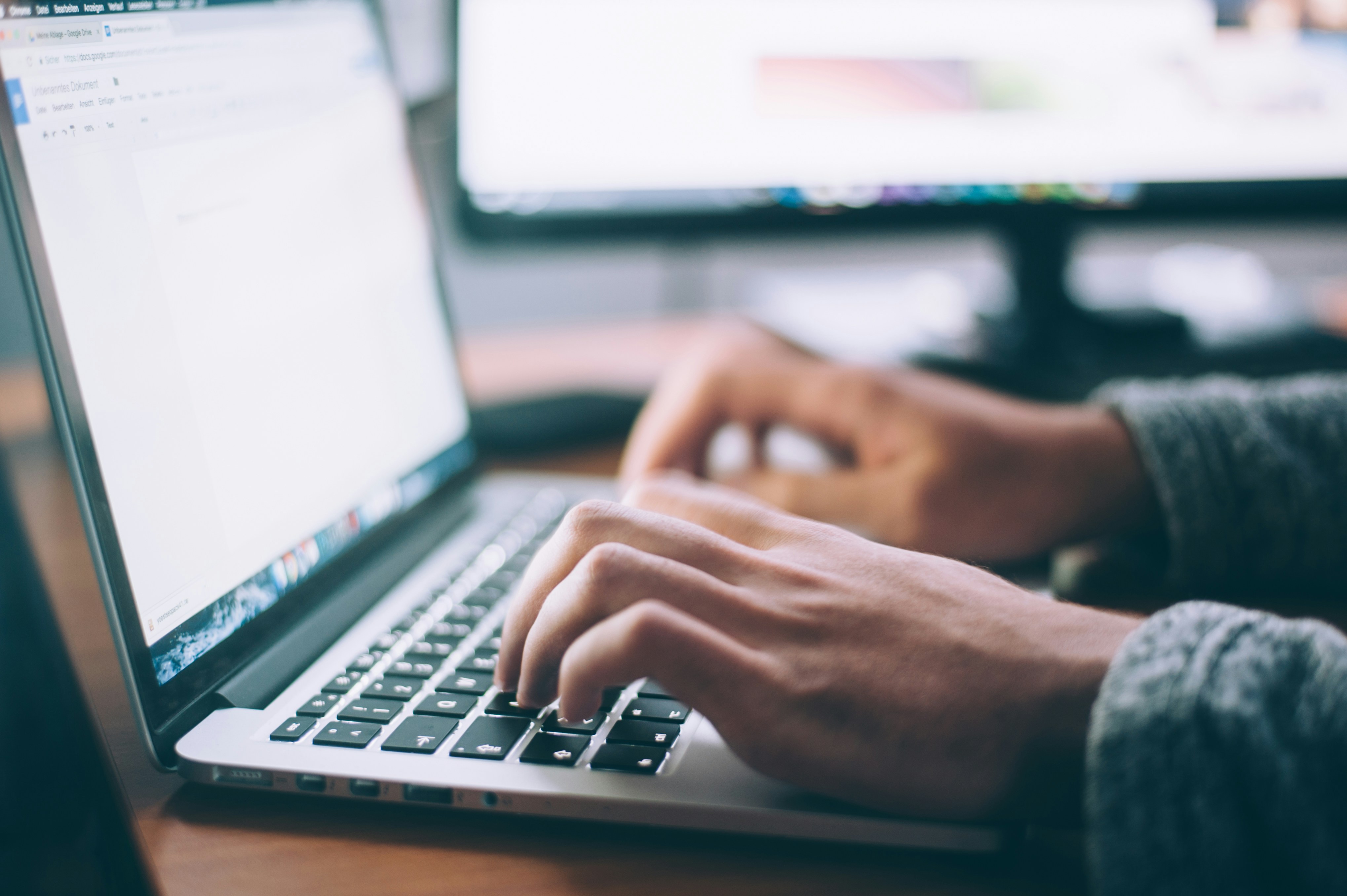 A man is sitting down at his desk working on his computer.